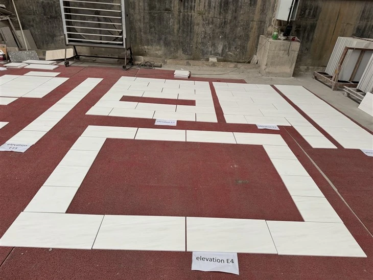 Honed Bianco Dolomite Marble tiles dry laid by numbered bathroom wall elevations to check the finished pieces against the approved shop drawings, vein layout and quality requirements before packing.