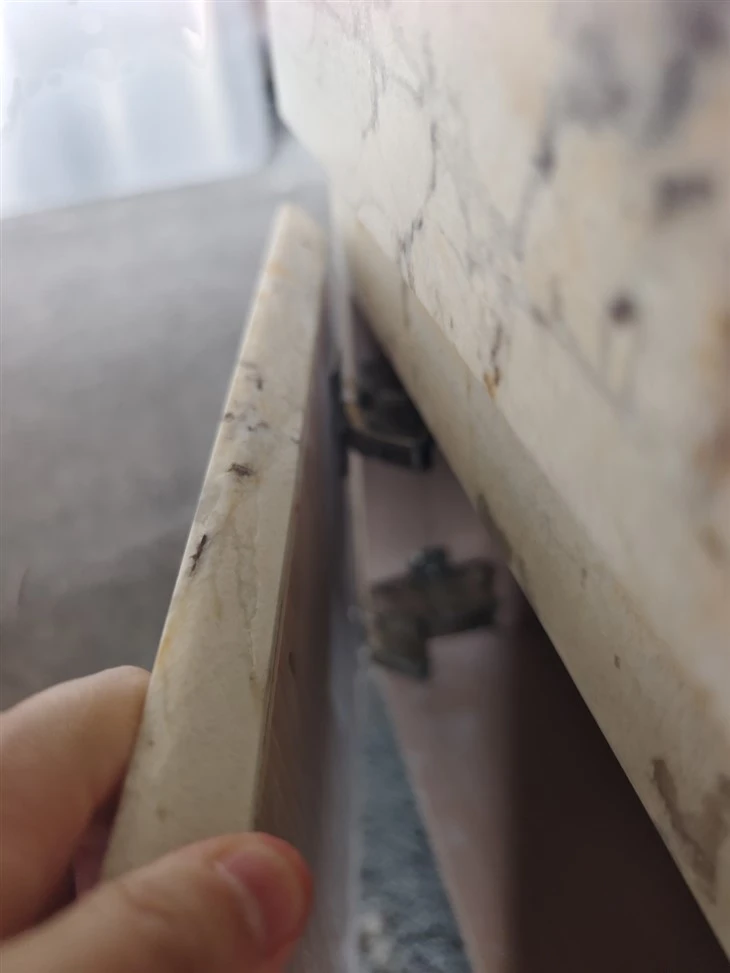Close inspection of the hinge, moving cabinet panel and surrounding stone cladding during functional testing.