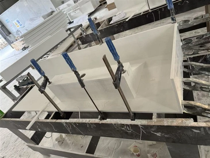 Cut white acrylic panels clamped and bonded to form the countertop, basin walls and integrated sink assembly.