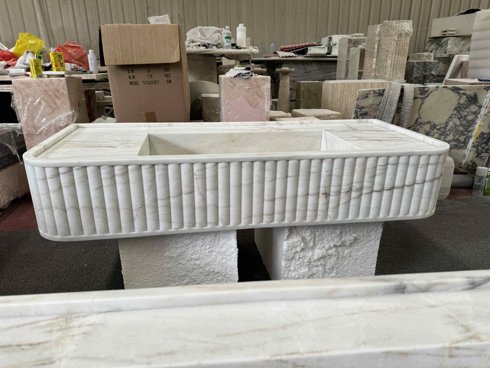 Dione Spider Marble countertop with integrated sink, curved front edge, and fluted stone tiles during fabrication Dione Spider Marble countertop with integrated sink, curved front edge, and fluted stone tiles during fabrication