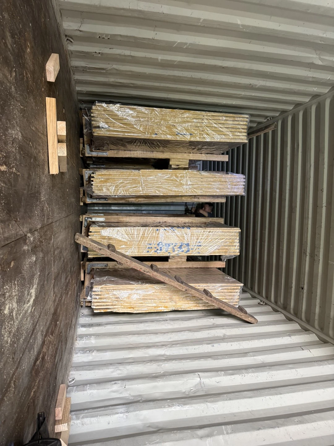 Interior view during loading of the first container showing wrapped marble slab bundles, support frames and timber packing components. Interior view during loading of the first container showing wrapped marble slab bundles, support frames and timber packing components.