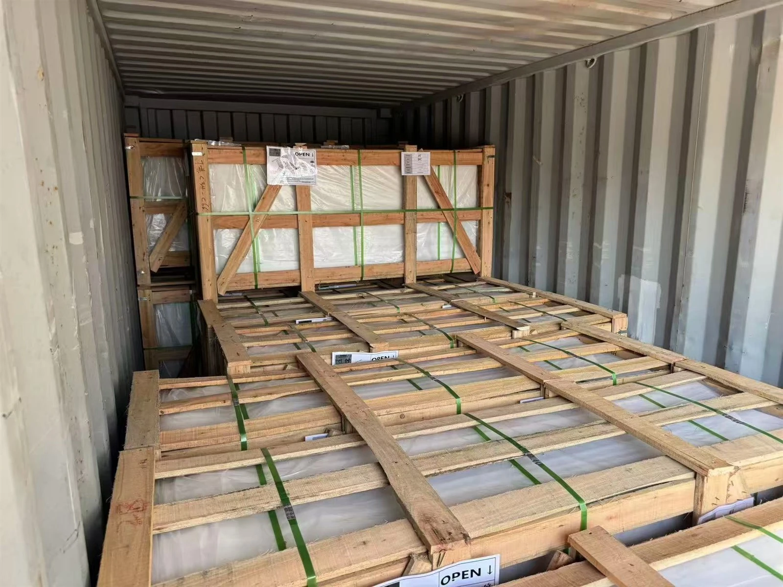 Wooden crates containing Calacatta White quartz shower wall panels positioned inside a shipping container during loading. Wooden crates containing Calacatta White quartz shower wall panels positioned inside a shipping container during loading.