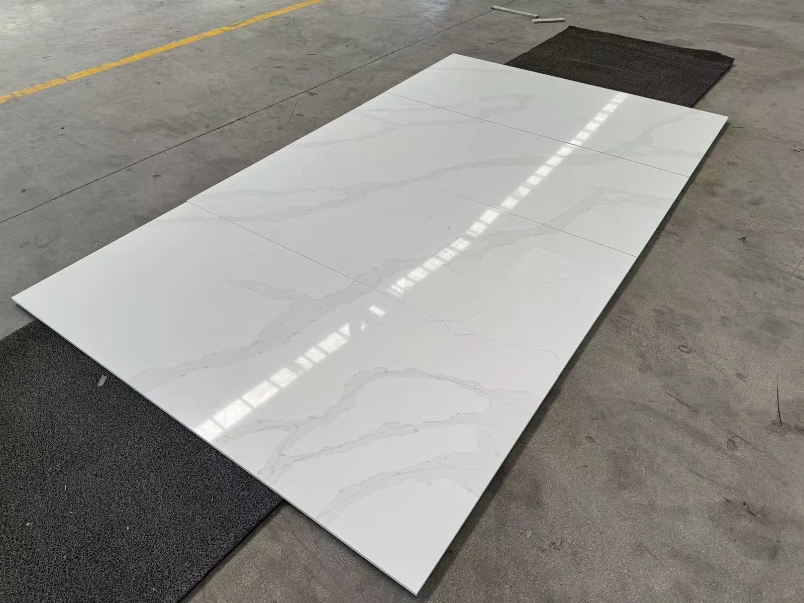 Finished Calacatta White engineered quartz shower wall panels arranged on the factory floor for surface and dimensional inspection before packing. Finished Calacatta White engineered quartz shower wall panels arranged on the factory floor for surface and dimensional inspection before packing.